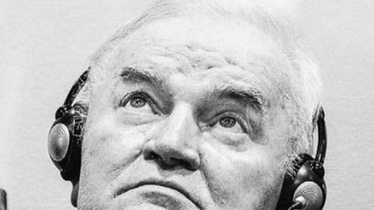 Ratko Mladic, de fones de tradução, olha para cima durante audiência no tribunal de Haia, em foto em preto e branco