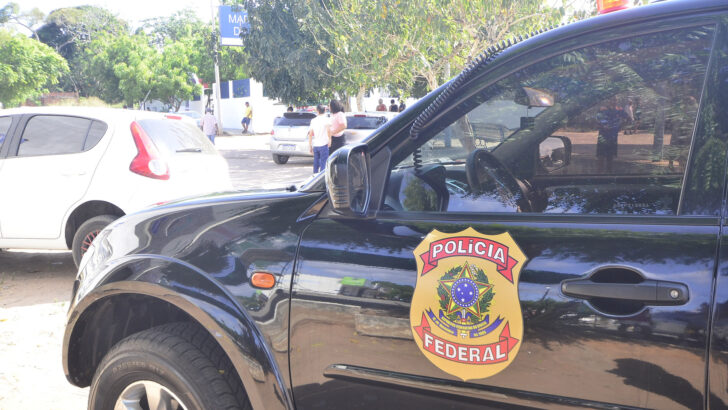 Viatura da Polícia Federal estacionada, com o brasão da corporação na porta.