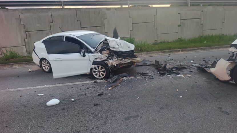 Carro com a parte dianteira destruída após colisão, com destroços espalhados pela pista