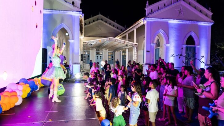 Artista no palco interage com crianças e famílias no Solar Bela Vista à noite