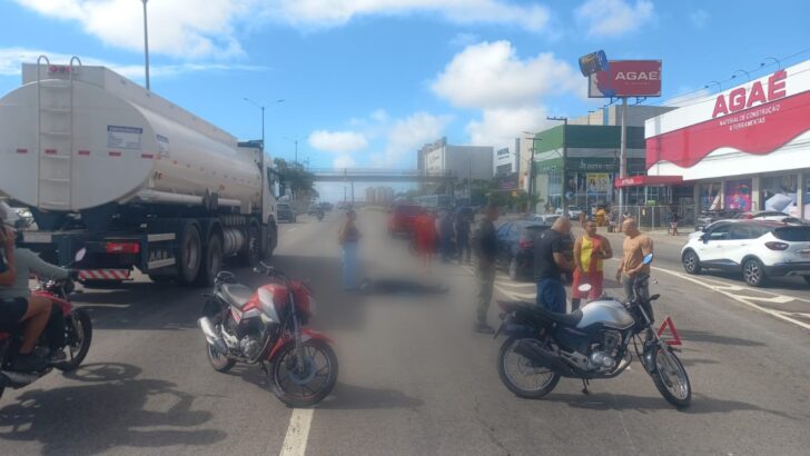 Motocicletas paradas na BR-101 e pessoas reunidas no local de um acidente, próximo a estabelecimentos comerciais em Natal