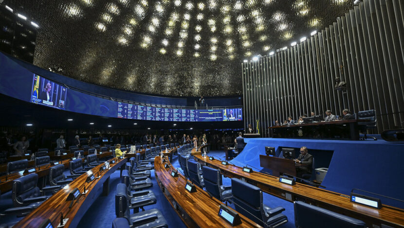 Vista ampla do plenário do Senado Federal, com cadeiras e mesas dos parlamentares e a Mesa Diretora ao fundo