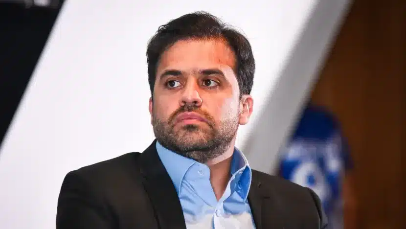 Homem de terno escuro e camisa azul durante evento