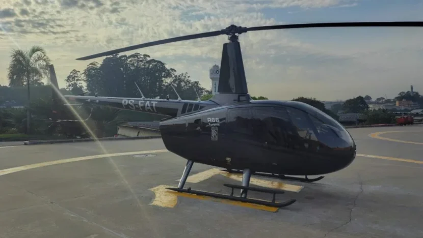Helicóptero Robinson R66 preto estacionado em área de pouso