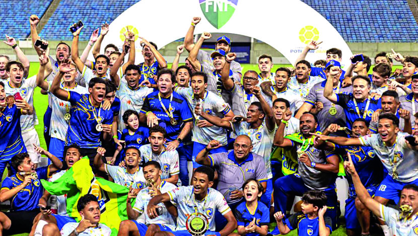 Jogadores e integrantes do QFC comemoram o título com troféu e medalhas no gramado