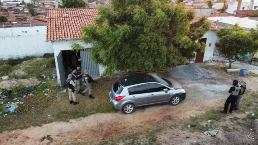 Agentes de segurança durante operação em área residencial, com veículo estacionado diante de um imóvel