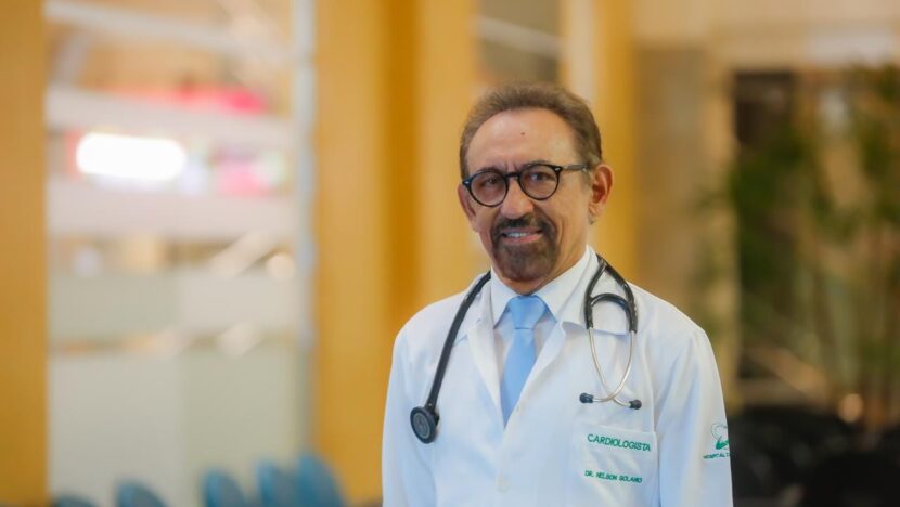 Médico cardiologista usando jaleco branco e estetoscópio em ambiente hospitalar