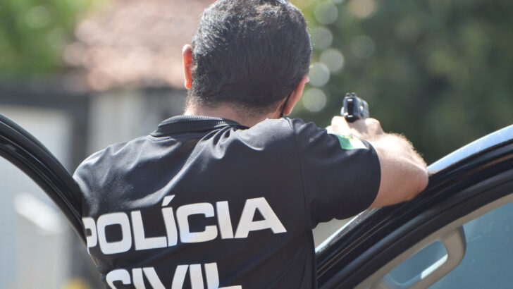 Agente da Polícia Civil do Rio Grande do Norte, de costas, com o fardamento da corporação durante ação