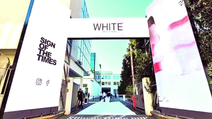 Portal de entrada da feira White Milano, com o nome do evento em um arco branco e a frase Sign of the Times na parede lateral