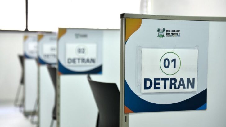 Guichês de atendimento do Detran-RN numerados, com divisórias e cadeiras vazias