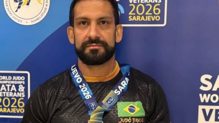 Judoca de quimono azul diante de painel com a inscrição World Judo Championships Veterans 2026 Sarajevo