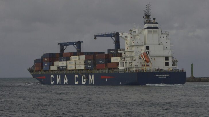 Navio de carga carregado de contêineres coloridos navega em mar agitado sob céu nublado