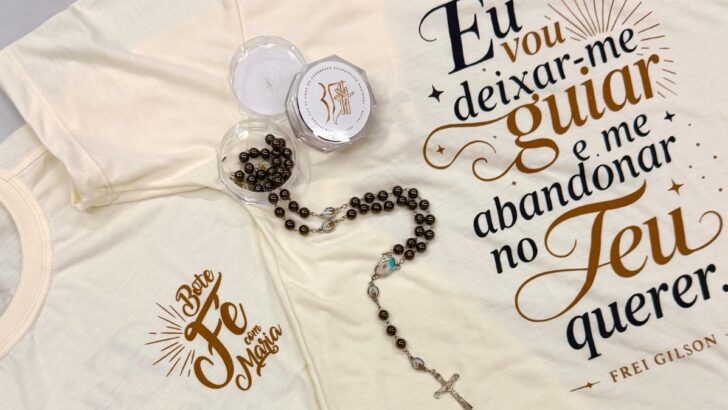 Camisetas cor creme com frase de Frei Gilson e o logotipo do Bote Fé, ao lado de um terço marrom e sua caixinha