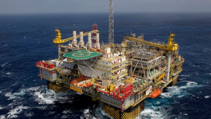 Plataforma de produção de petróleo com heliponto e guindastes amarelos em mar aberto