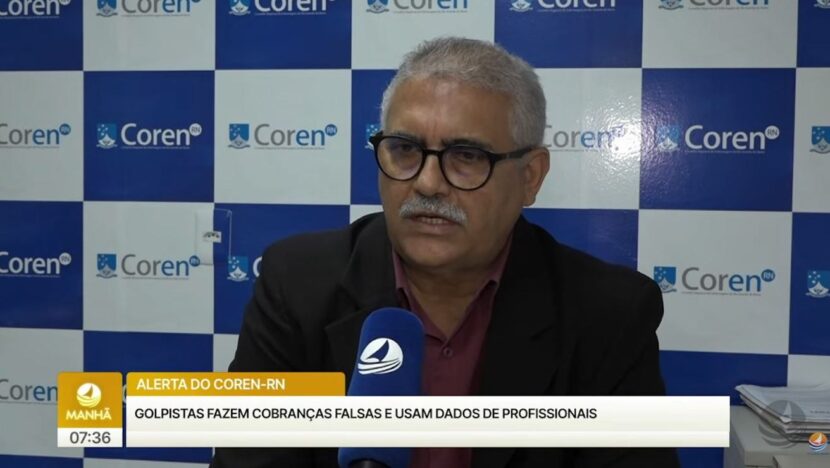 Homem de óculos e terno escuro fala ao microfone diante de painel azul com a marca do Coren