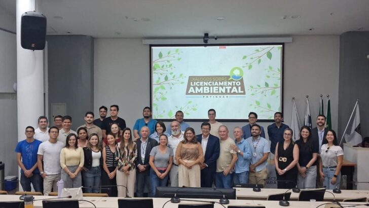 Grupo de pessoas posa em pé num auditório, diante de telão com a expressão licenciamento ambiental