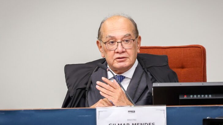 Ministro de toga preta e óculos gesticula sentado à bancada do plenário