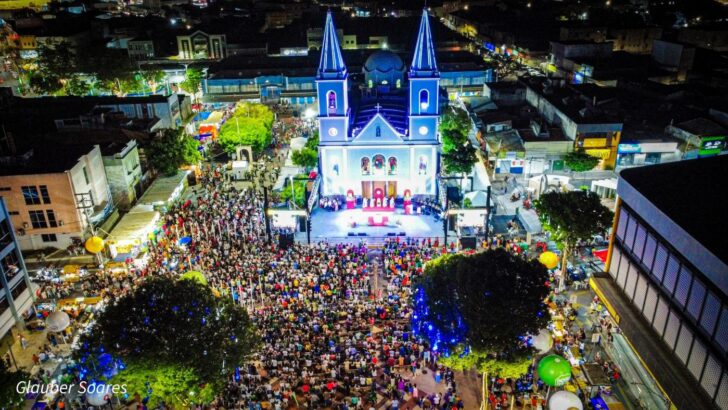 Vista aérea noturna de multidão reunida na praça em frente a catedral iluminada de azul