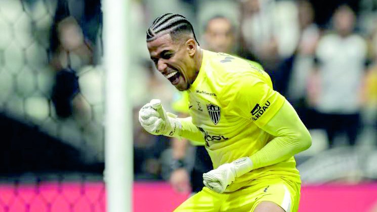 Goleiro de uniforme claro comemora aos gritos com o punho cerrado