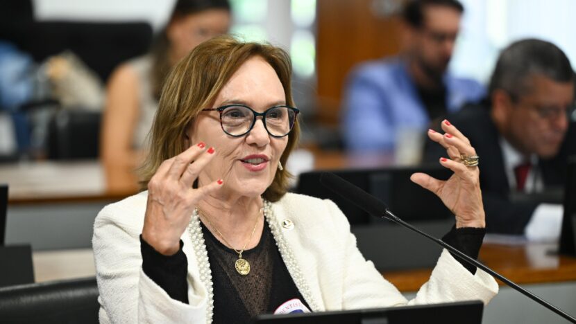 Senadora de óculos e blazer branco gesticula ao falar em comissão