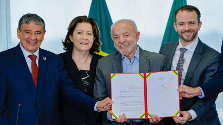 Presidente Lula mostra decreto assinado ao lado de ministros, diante de bandeiras