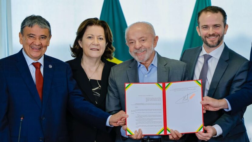 Presidente Lula mostra decreto assinado ao lado de ministros, diante de bandeiras