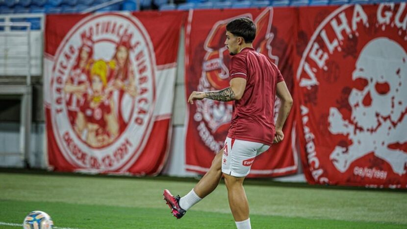 Jogador de camisa vermelha do América domina a bola em treino no estádio