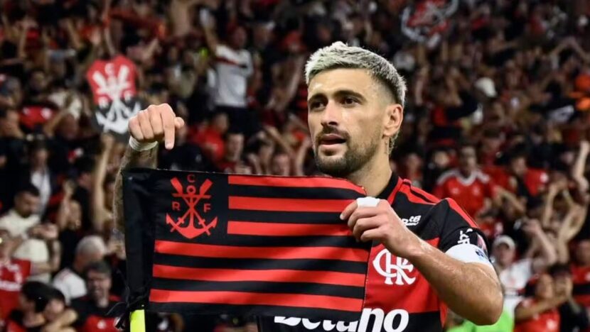 Jogador do Flamengo segura bandeira rubro-negra diante da torcida no Maracanã