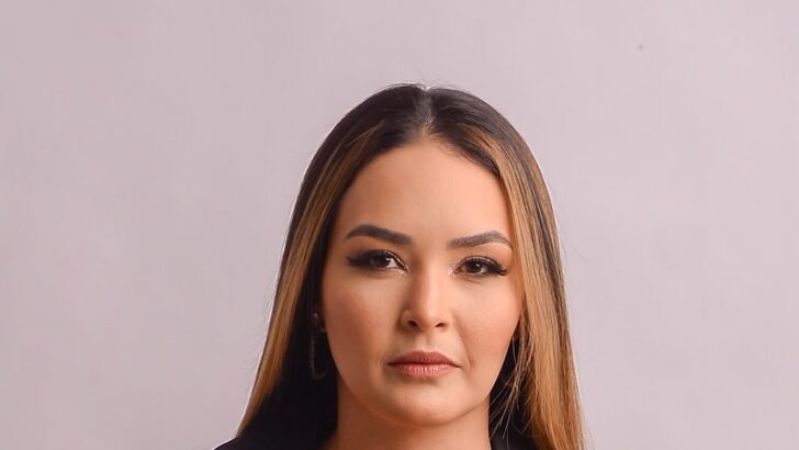 Retrato de mulher de cabelos longos e roupa escura diante de fundo claro