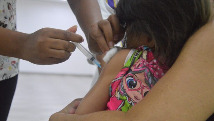 Profissional de saúde aplica vacina no braço de uma criança