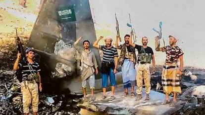 Homens armados posam sobre destroços de aeronave com a bandeira da Arábia Saudita