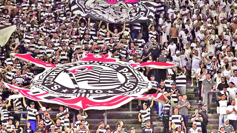 Arquibancada lotada de torcedores do Corinthians com bandeirão do clube na Neo Química Arena