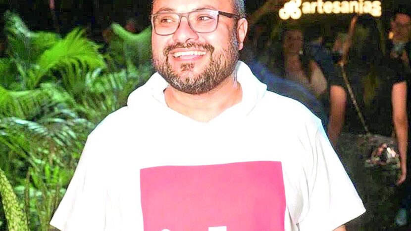 Estilista George Azevedo, de camisa branca, posa sorrindo para foto