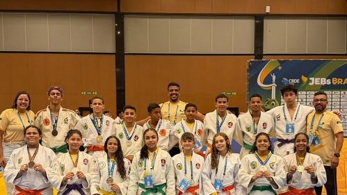 Jovens judocas com quimonos e medalhas posam com a bandeira do RN