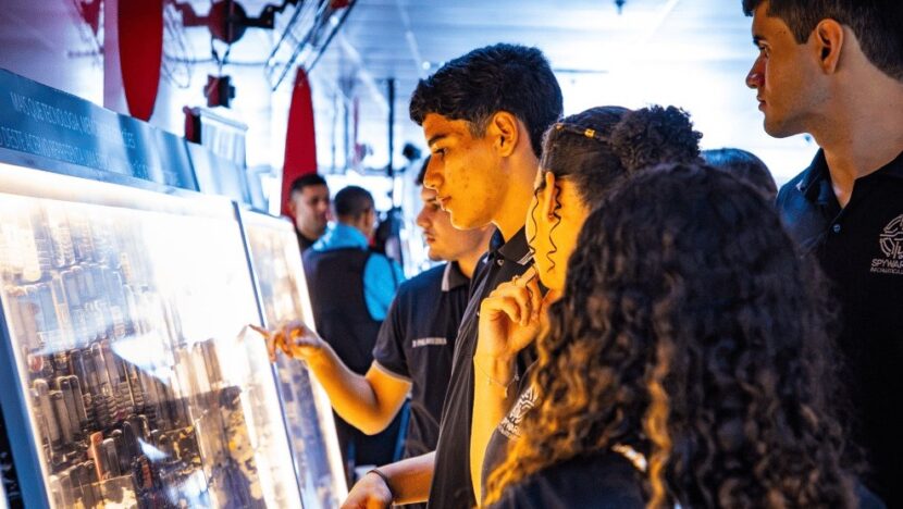Jovens observam equipamentos antigos expostos em painel