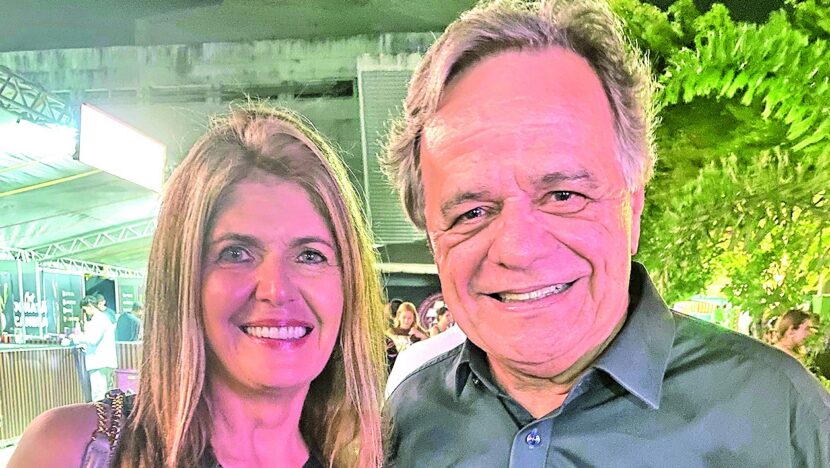 Mulher e homem sorriem lado a lado em evento noturno
