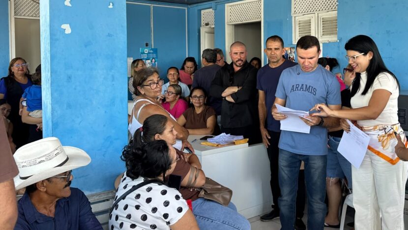 Pessoas reunidas em sala de unidade de saúde durante entrega de documentos