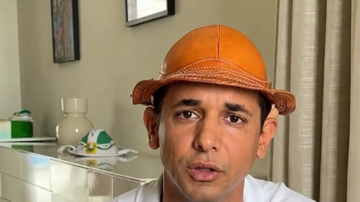 Homem de chapéu de couro e camisa branca fala sentado em uma sala