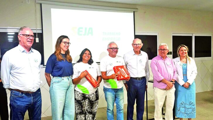 Grupo de pessoas posa em auditório; participantes seguram certificados