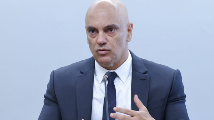 Ministro Alexandre de Moraes fala ao microfone sob o brasão da República