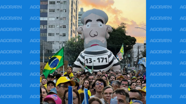 Boneco inflável de Lula com roupa listrada e inscrição “13-171” aparece acima de manifestantes com bandeiras do Brasil no Largo do Atheneu, em Natal.