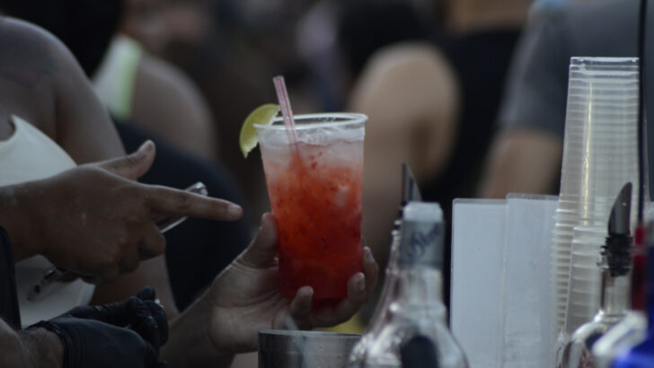 Drinque com gelo e rodela de limão servido no balcão de um bar