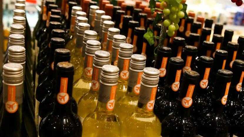 Garrafas de vinho tinto e branco expostas em prateleira de supermercado