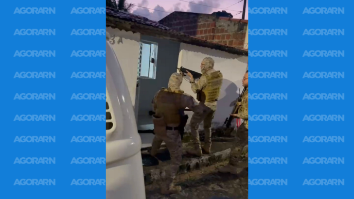 Agentes armados durante diligência policial em frente a um imóvel