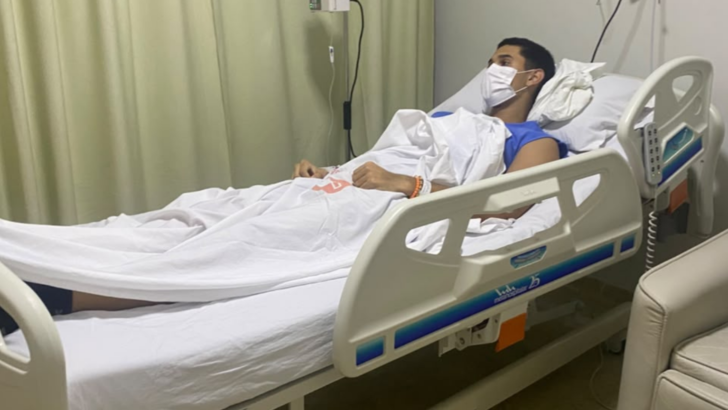 Jovem usando máscara de proteção deitado em leito hospitalar durante tratamento