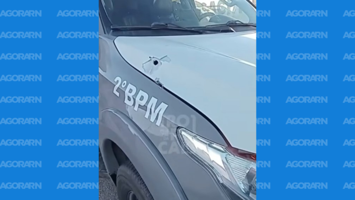 Detalhe de viatura da Polícia Militar com perfuração e danos na parte dianteira do veículo