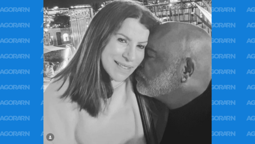 Registro em preto e branco mostra uma mulher ao lado de um homem, que aparece beijando seu rosto
