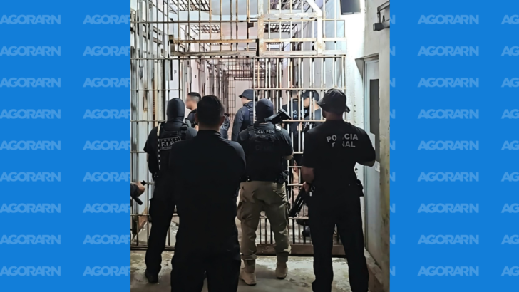 Policiais penais em corredor com grades no interior de unidade prisional durante operação de segurança