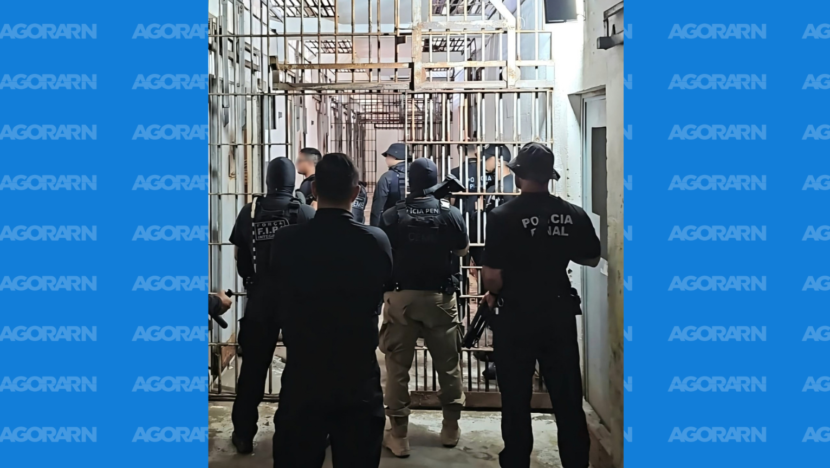 Policiais penais em corredor com grades no interior de unidade prisional durante operação de segurança