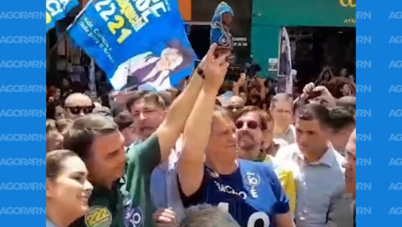 Dois homens erguem uma pequena imagem religiosa em meio a apoiadores durante ato de campanha